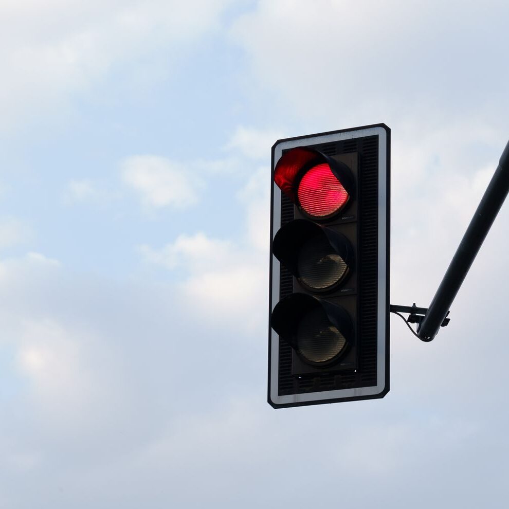 Feu rouge sur fond d'un ciel lumineux et nuageux.